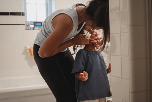 Young woman cleaning her daughter’s face