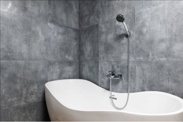 A white bathtub against a tiled grey wall