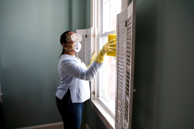 A woman cleaning the window using chemicals
