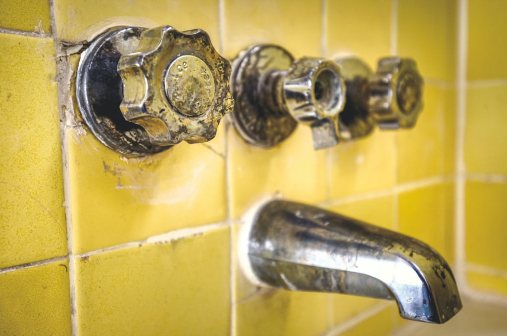 Stained fixtures and worn-off tiles in an old bathroom