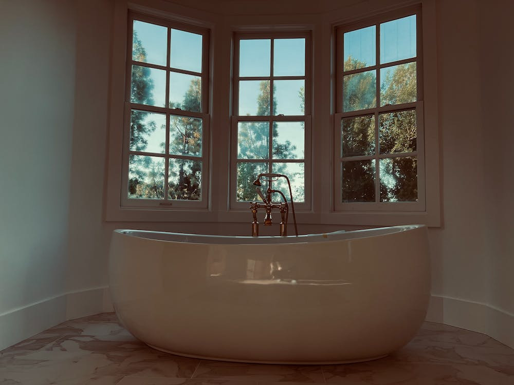 An image of a shiny white reglazed bathtub beneath a window